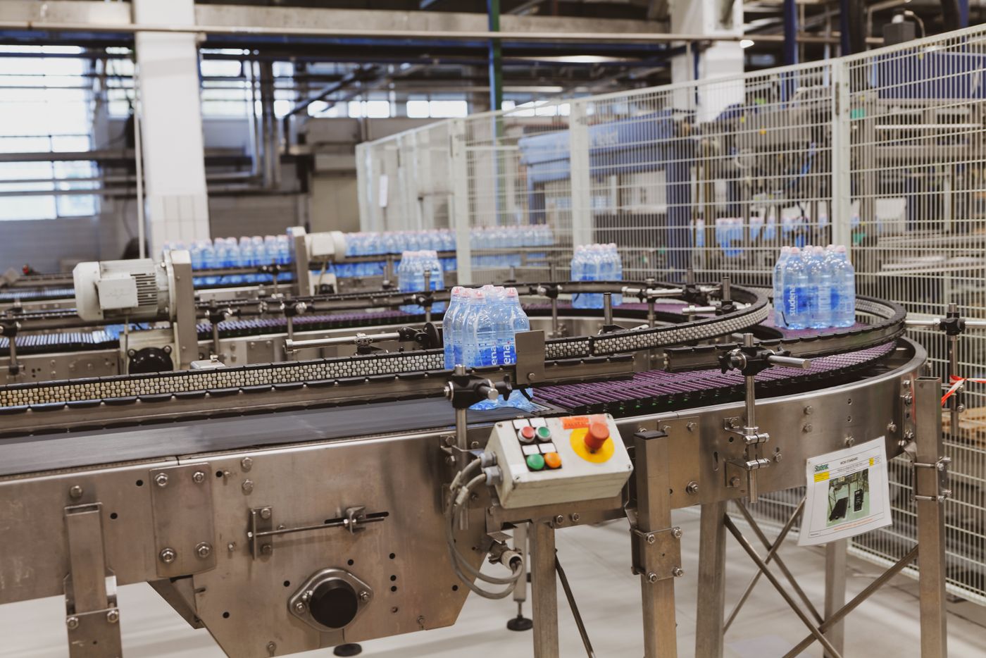 Ligne d'embouteillage : convoyage de bouteilles d'eau en PET après remplissage.